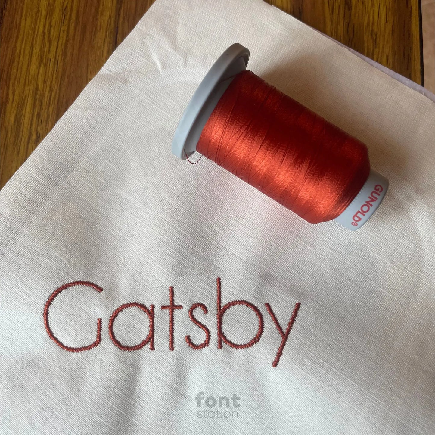Image showing a word embroidered on textile using the Art Deco embroidery font created by FontStation